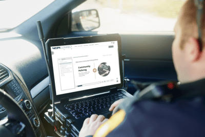 side view of police officer in his police cruiser using his laptop to take a course